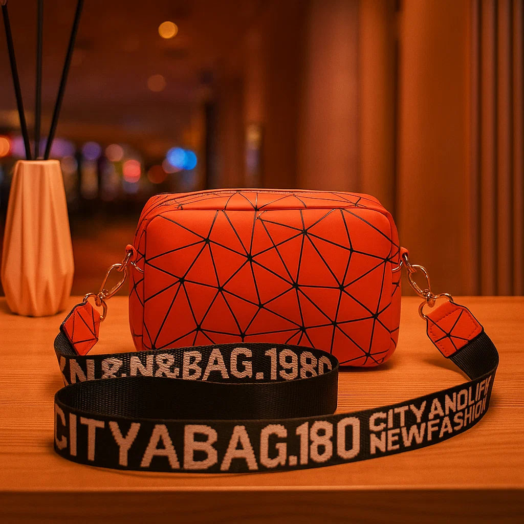 Red geometric-patterned bag with a black strap on a wooden surface