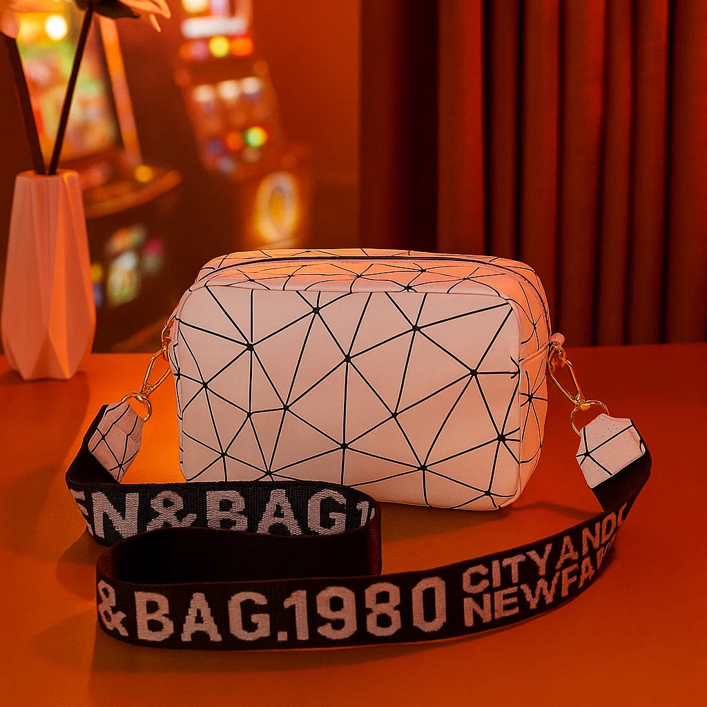 Geometric-patterned bag with a black strap featuring text on a warm-toned background